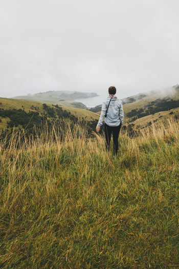 Young woman looking at little akaloa, banks peninsula, new zealand