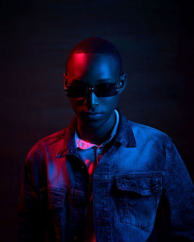 Young man wearing sunglasses against black background
