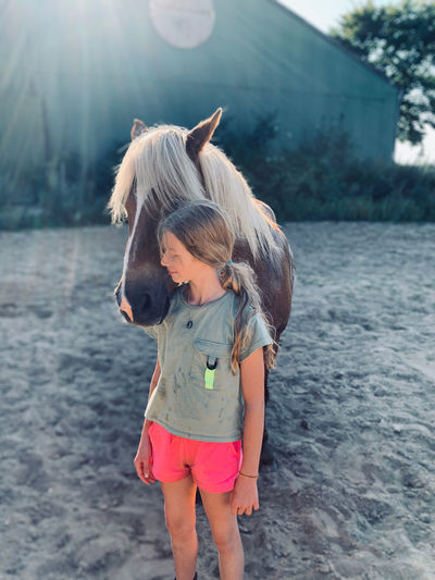 Cute girl standing with horse at stable