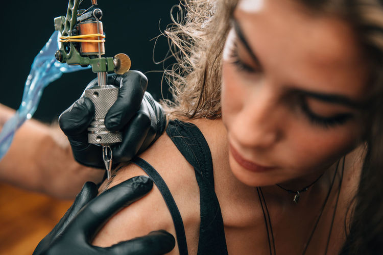 Close-up of mam making tattoo on woman back