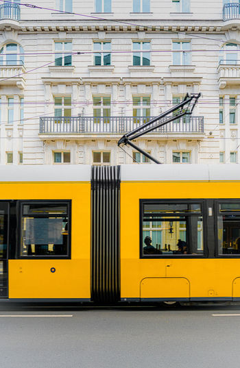 Yellow train on street against buildings in city
