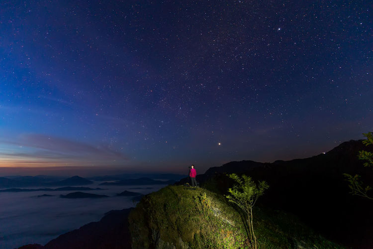 Woman on mountain against sky at night