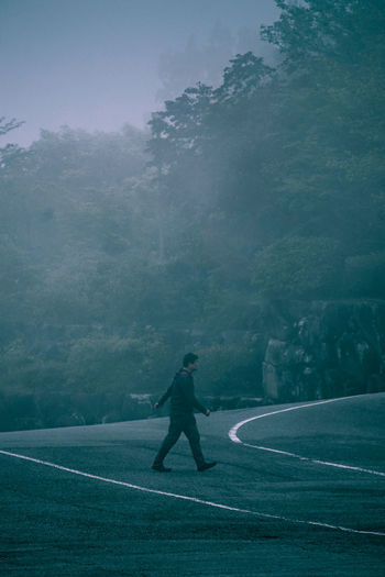 Man walking on road amidst trees