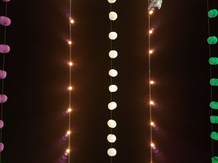 Low angle view of illuminated light bulbs hanging at night