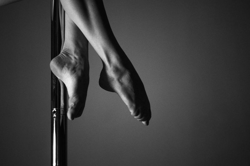 Low section of woman dancing on pole against wall