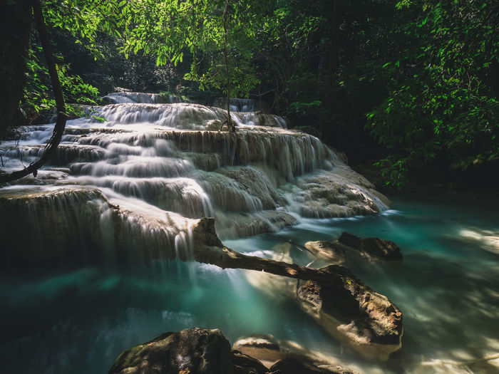 Epic waterfall smooth flowing stream with sunlight in forest. erawan falls, kanchanaburi, thailand.