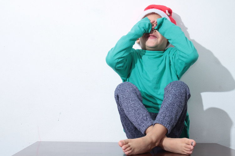 Full length of boy sitting against wall stock photo