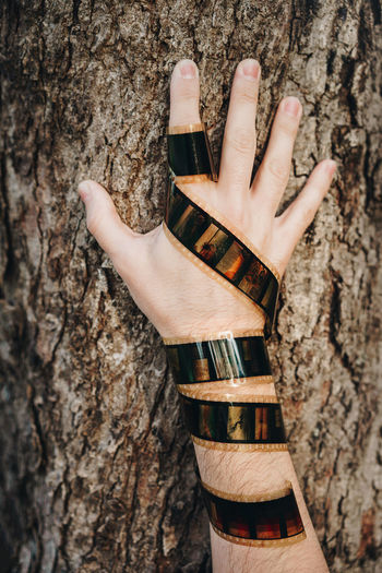 Cropped hand with reel against tree trunk