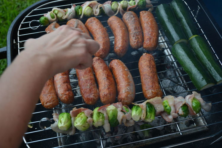 High angle view ofhand preparing meat and vegetables on barbecue grill