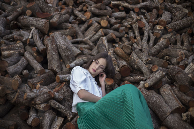 Woman with melancholic and romantic vintage clothes leaning on wooden logs
