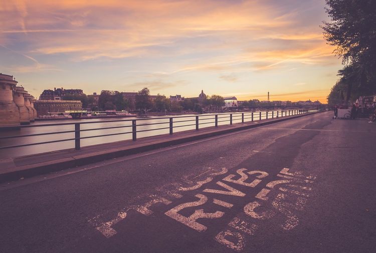 Road by city against sky during sunset