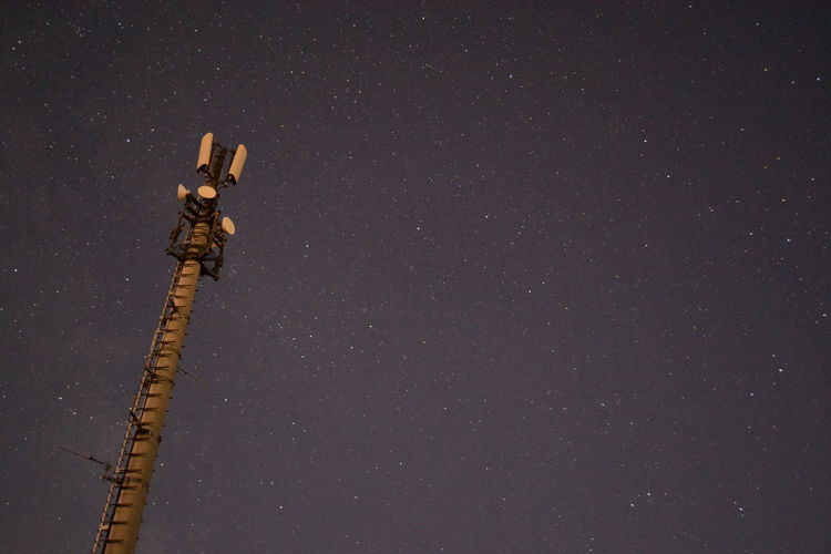 Low angle view of communications tower against star field sky at night