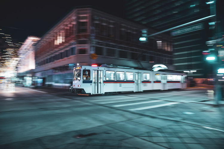 Train on illuminated street in city at night