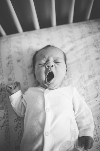 Close-up of baby girl yawning in crib
