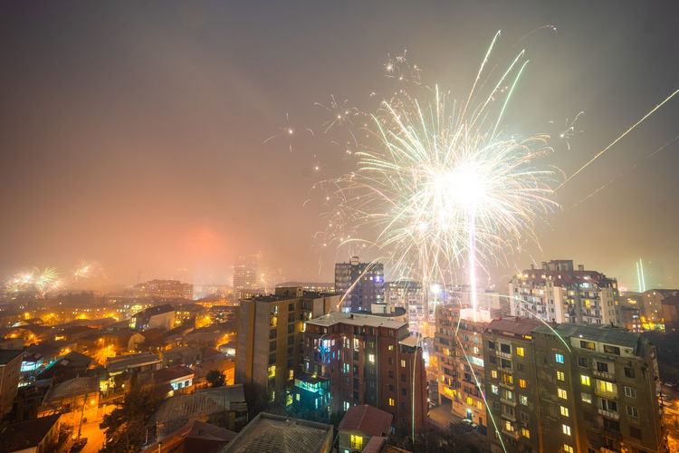 High angle view of firework display over buildings in city