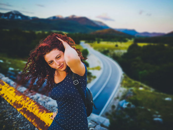 Portrait of smiling young woman standing on road