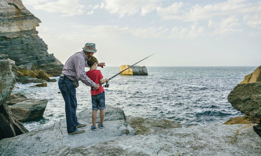 Grandfather and grandson fishing together at the sea
