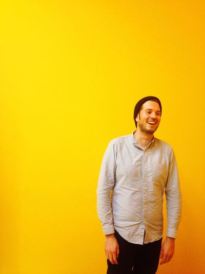 Cheerful young man standing against yellow background