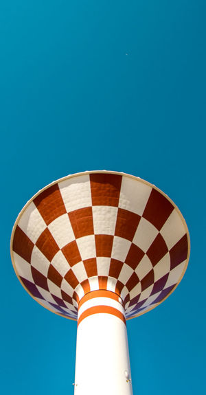Low angle view of water tower against clear blue sky