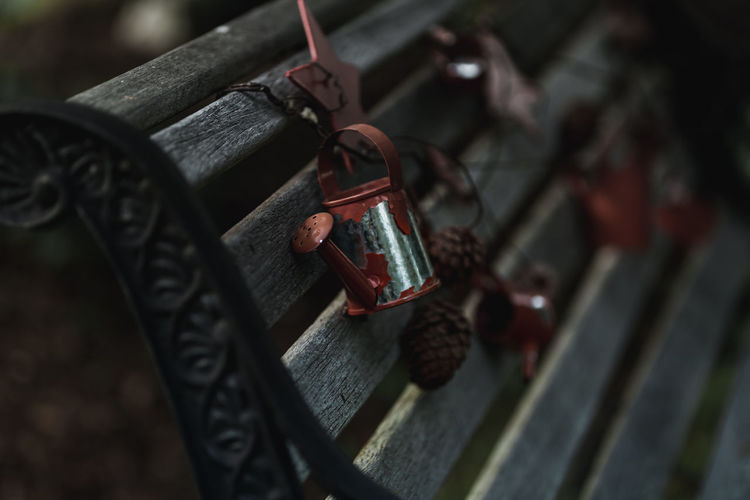 Close-up of watering can figurine hanging on bench outdoors