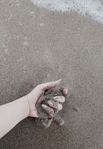 High angle view of person hand on sand