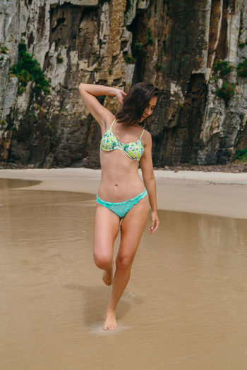 Rear view of woman in bikini standing on beach