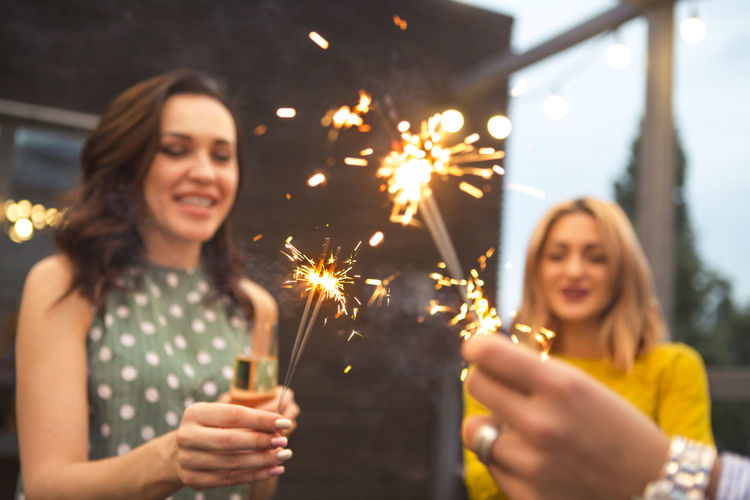 Close-up of female friends holding sparklers in yard