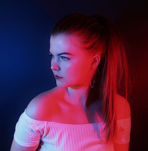 Portrait of beautiful young woman with red lighting