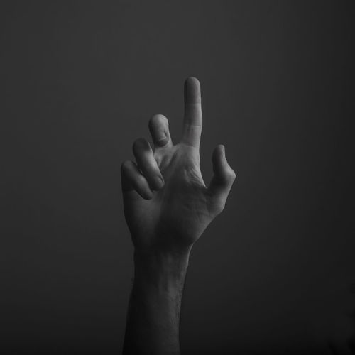 Close-up of human hand gesturing against black background