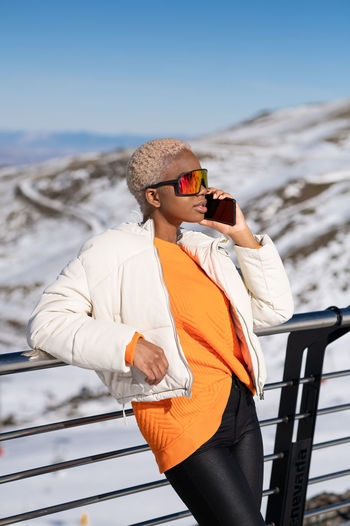 A young african american woman wearing sunglasses having fun in the snow on a winter day