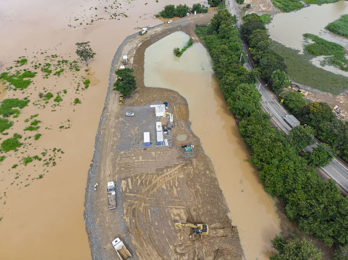 River flooding due to rain causes large mud next to a dam that prevents the rivers from meeting 