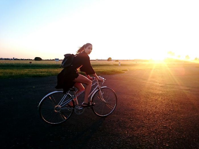 People riding bicycle on road at sunset