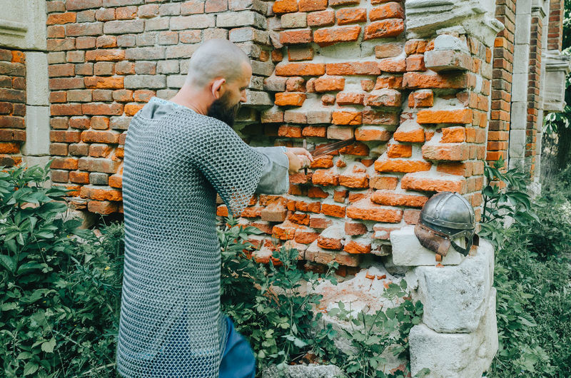 Rear view of man standing against brick wall