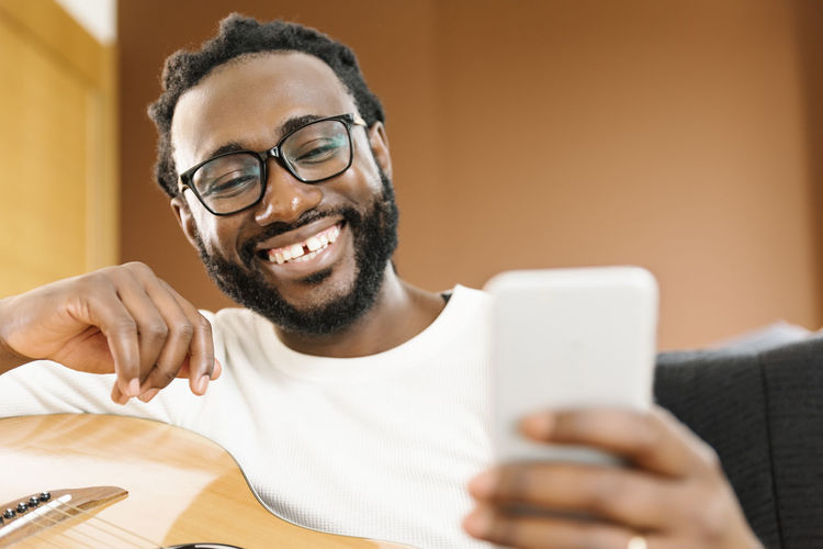 Smiling man using phone while sitting in studio