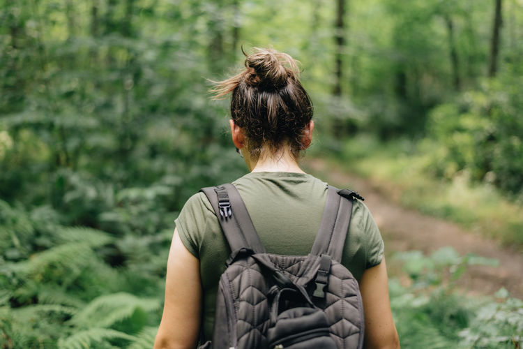 Young millennial woman outdoors on trail with backpack going hiking