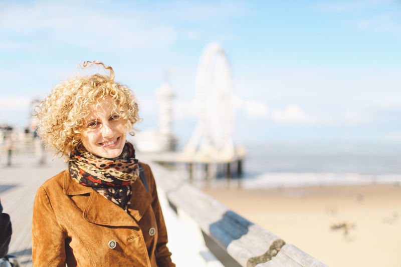 Portrait of smiling woman standing by beach