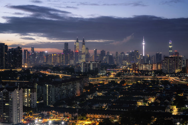 Illuminated buildings in city against sky