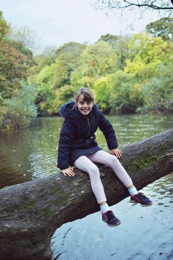 Portrait of girl on river against trees