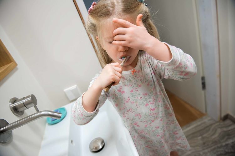 Girl brushing teeth in bathroom at home