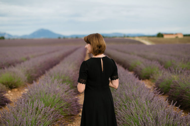 Rear view of woman standing between blossoms of lavender field 