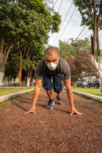 Full length of man with mask exercising outdoors