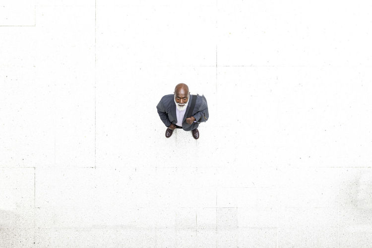 Senior businessman standing on white flooring at railroad station