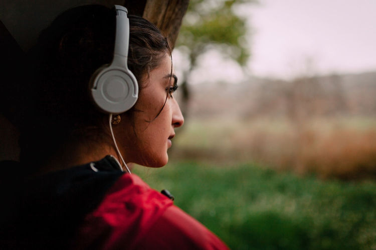 Close-up of young woman looking away listening to music