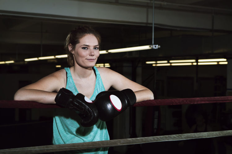 Portrait of smiling sportswoman standing in boxing ring at gym