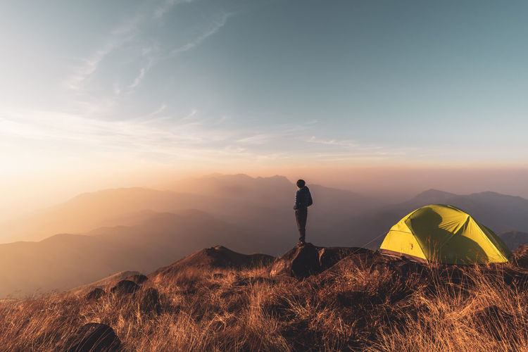 Man standing on mountain against sky during sunrise