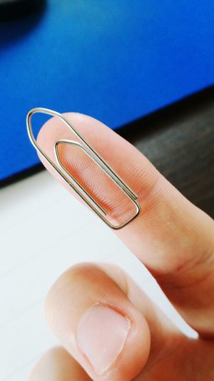 Close-up of hand holding paper clip