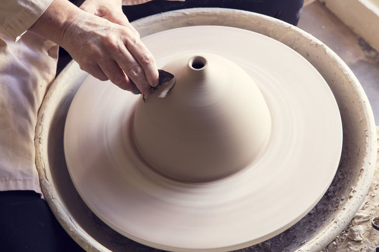 High angle view of woman molding shape to clay on pottery wheel