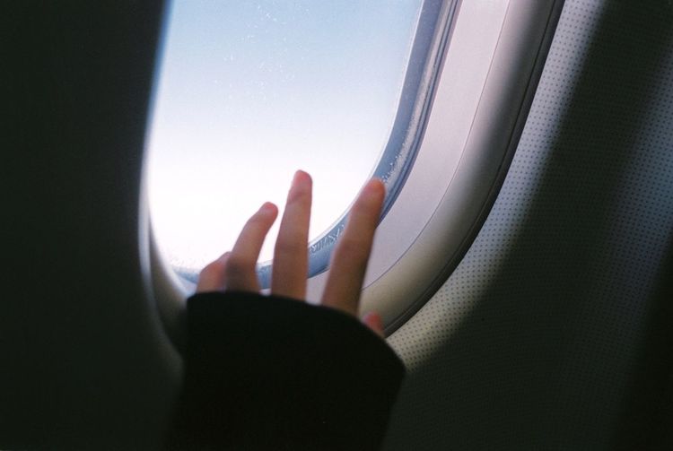 Cropped image of hand on window of airplane
