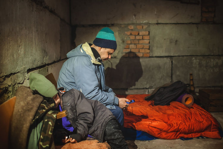 Side view of man using mobile phone at shelter