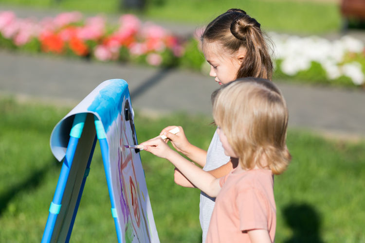 Side view of girls painting outdoors